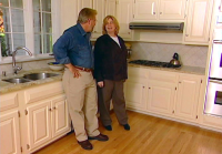 Man and women standing in kitchen in front of cabinets