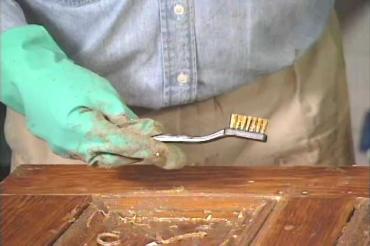 using a metal brush to stip off old paint