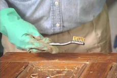 using a metal brush to stip off old paint